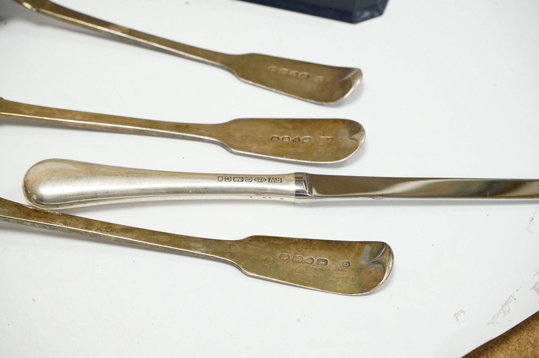 Three assorted George III silver fiddle pattern table spoons, a modern silver spirit label, ‘’Brandy’’, two silver letter openers and a heavy silver serviette ring. Condition - poor to fair to good